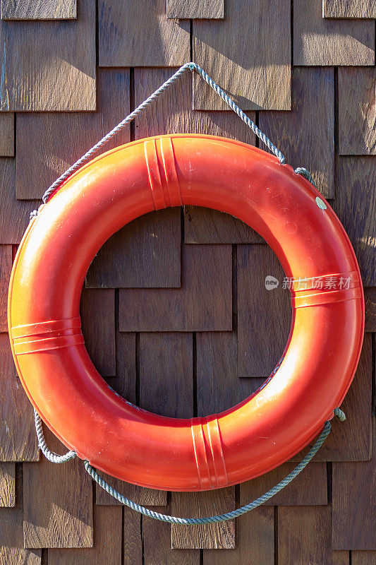 橙色救生圈/救生带应急设备装置悬挂在浮水船房/家外甲板的墙壁上。